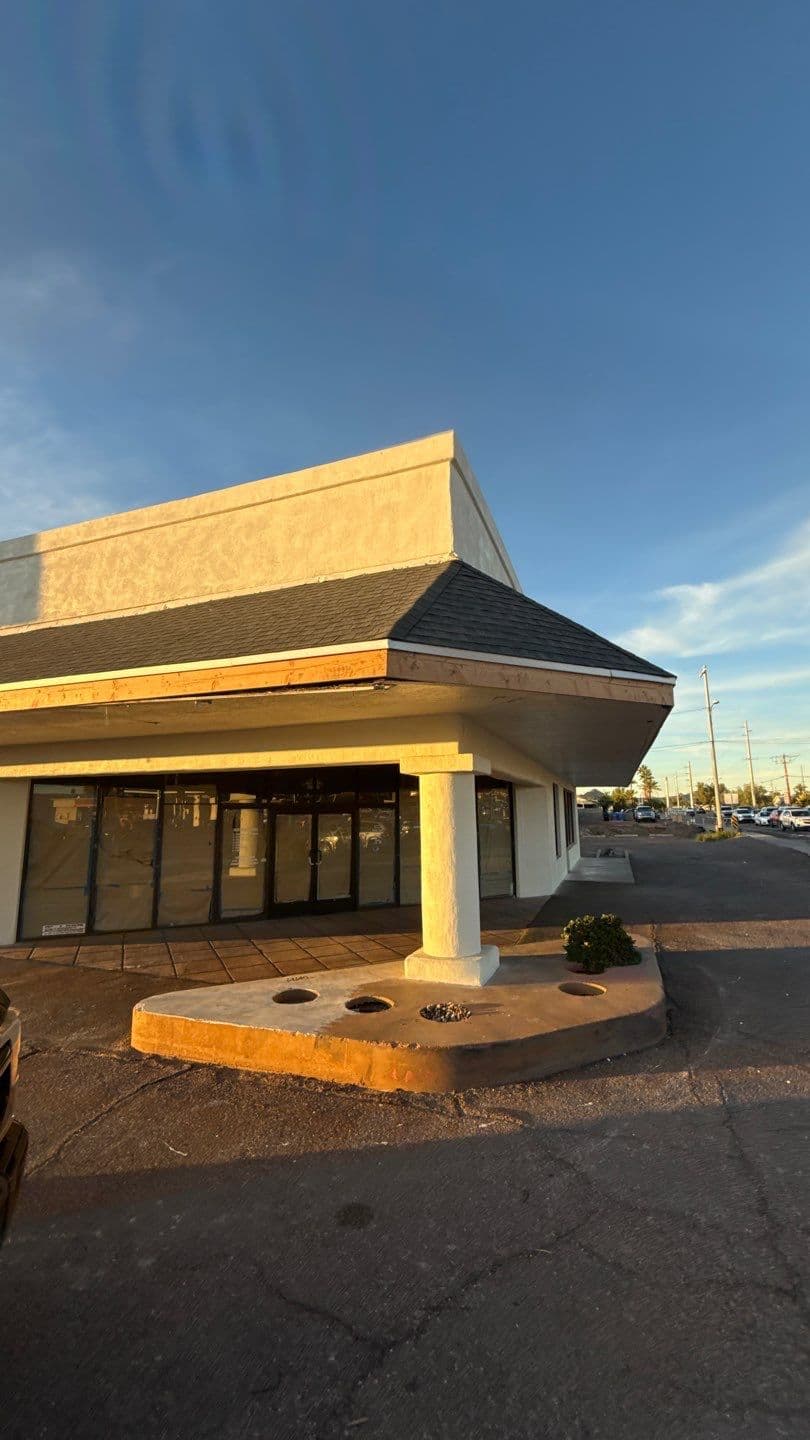 Abandoned retail building with a unique architectural design and clear blue sky background.